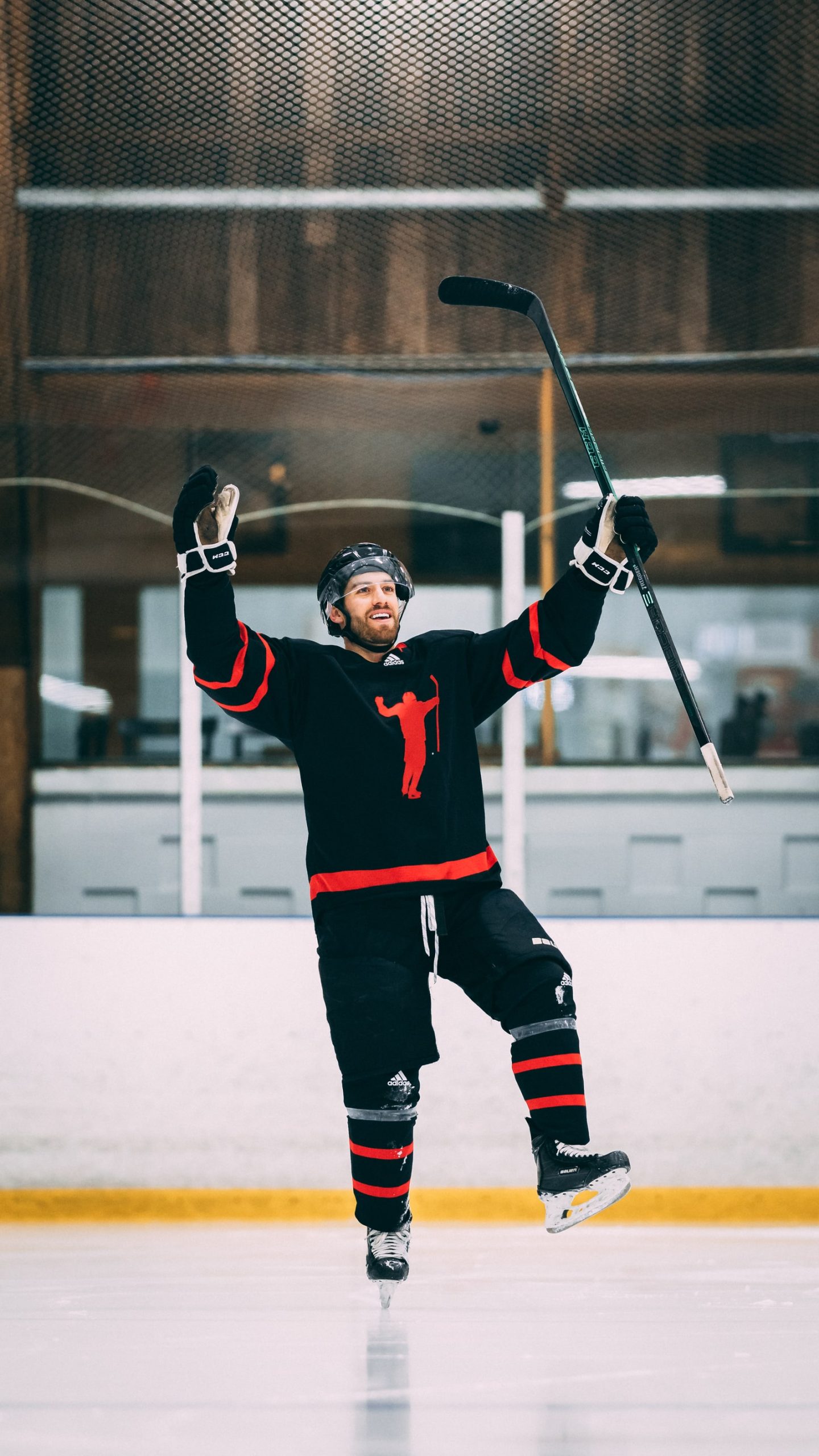 Coach Kevin celebrating on the ice with his arms raised.