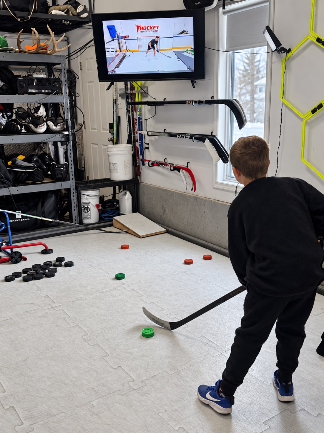 Young player following a Hockey Training stickhandling video on a TV in the garage.